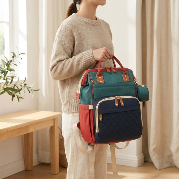 Stylish red colorblock diaper bag being held by a person in a cozy setting.